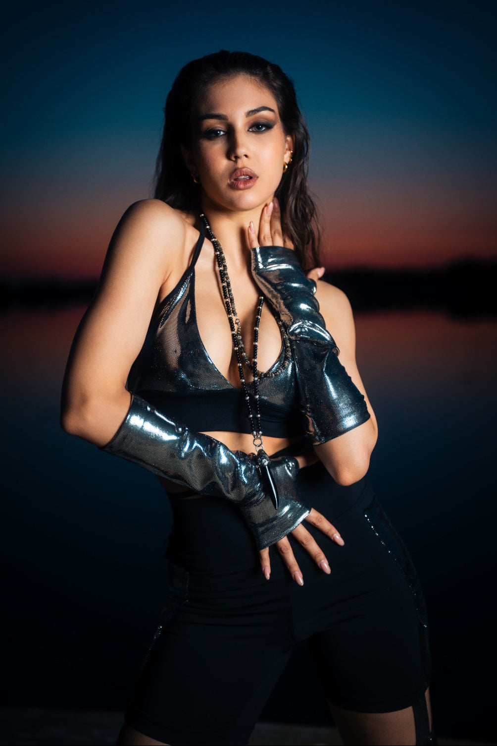 Woman wearing a black outfit with metallic gloves against a dark background
