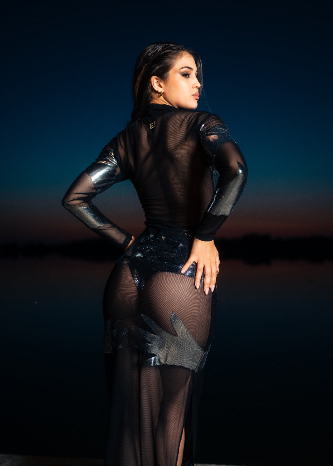 Woman wearing a black sheer outfit with a dark background