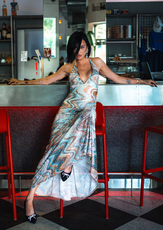 Woman in a patterned dress leaning on a bar counter in a bar setting